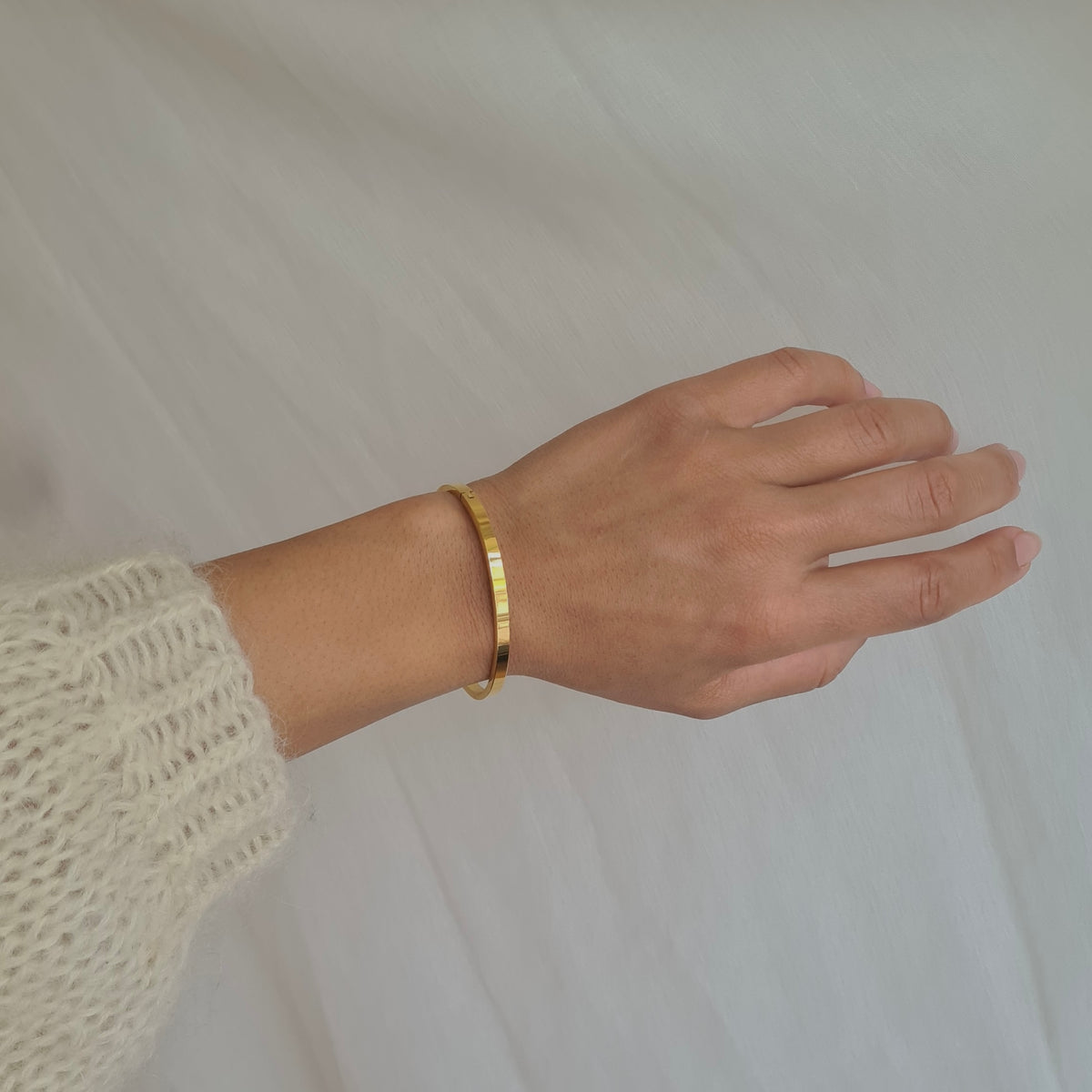 Håndled med Kaja guld bangle i forgyldt stål.